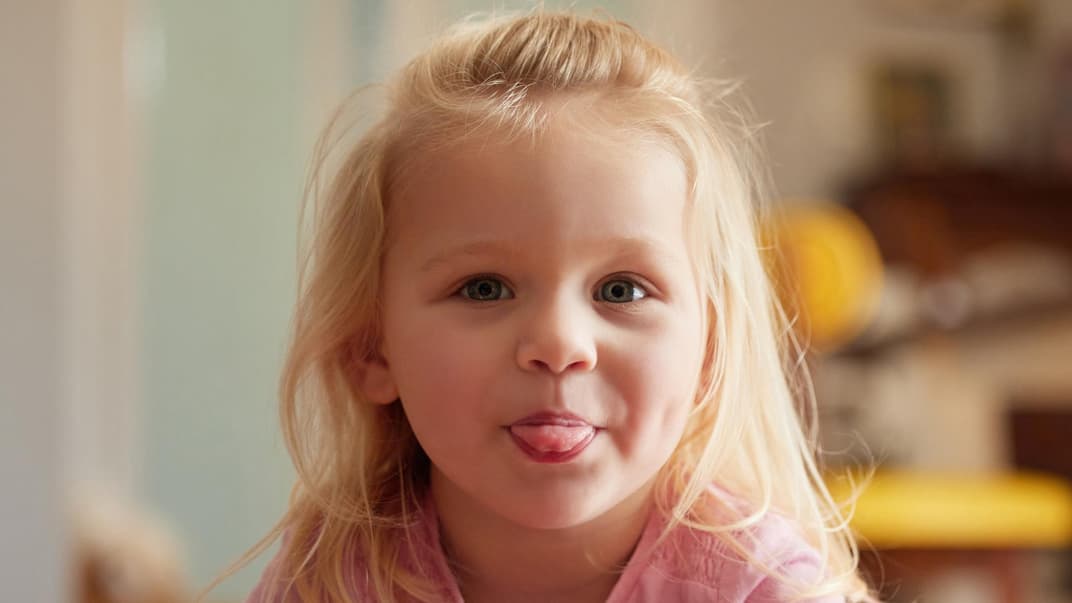 Die besten Aprilscherze für Kinder Ein kleines blondes Mädchen streckt die Zunge heraus.
