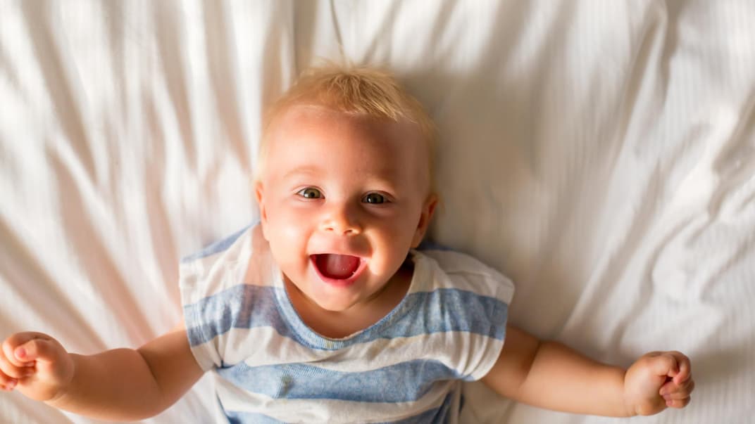 Baby-Junge liegt auf dem Bett und lacht. Baby-Junge liegt auf dem Bett und lacht.