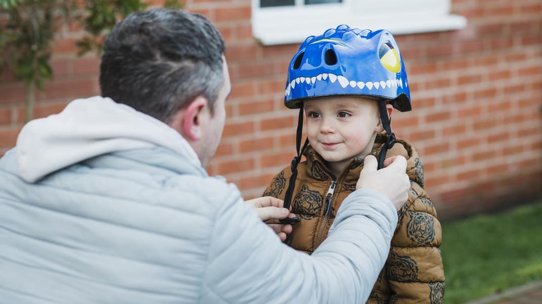 Im Winter: Mütze unterm Fahrradhelm oder lieber nicht? Ein Kind setzt einen Fahrradhelm auf