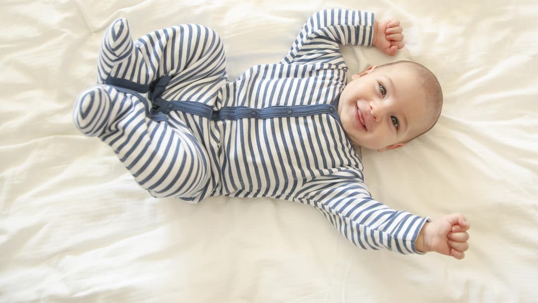 Baby-Junge in einem Strampler hat gute Laune und lacht. Baby-Junge in einem Strampler hat gute Laune und lacht.