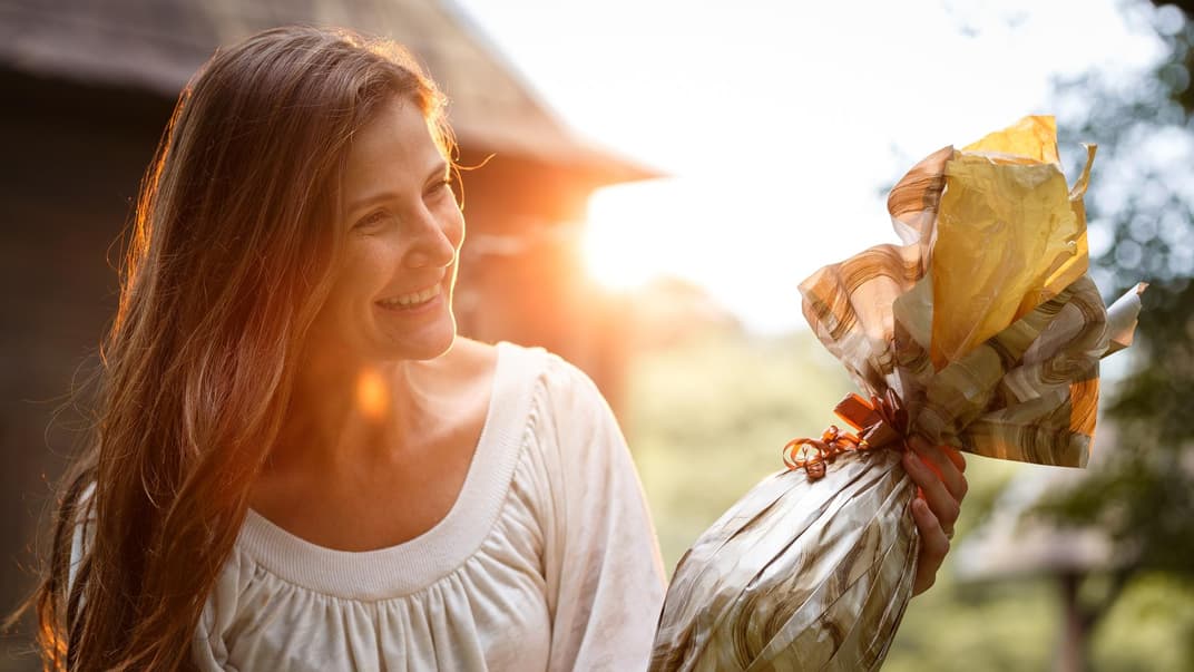 Eine Frau bekommt ein Ostergeschenk überreicht und freut sich. Eine Frau bekommt ein Ostergeschenk überreicht und freut sich.