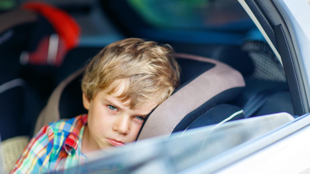 Darf man sein Kind alleine im Auto lassen? Dieses Frage stellen sich viele Eltern früher oder später. Ein kleiner Junge schaut aus dem offenen Autofenster.