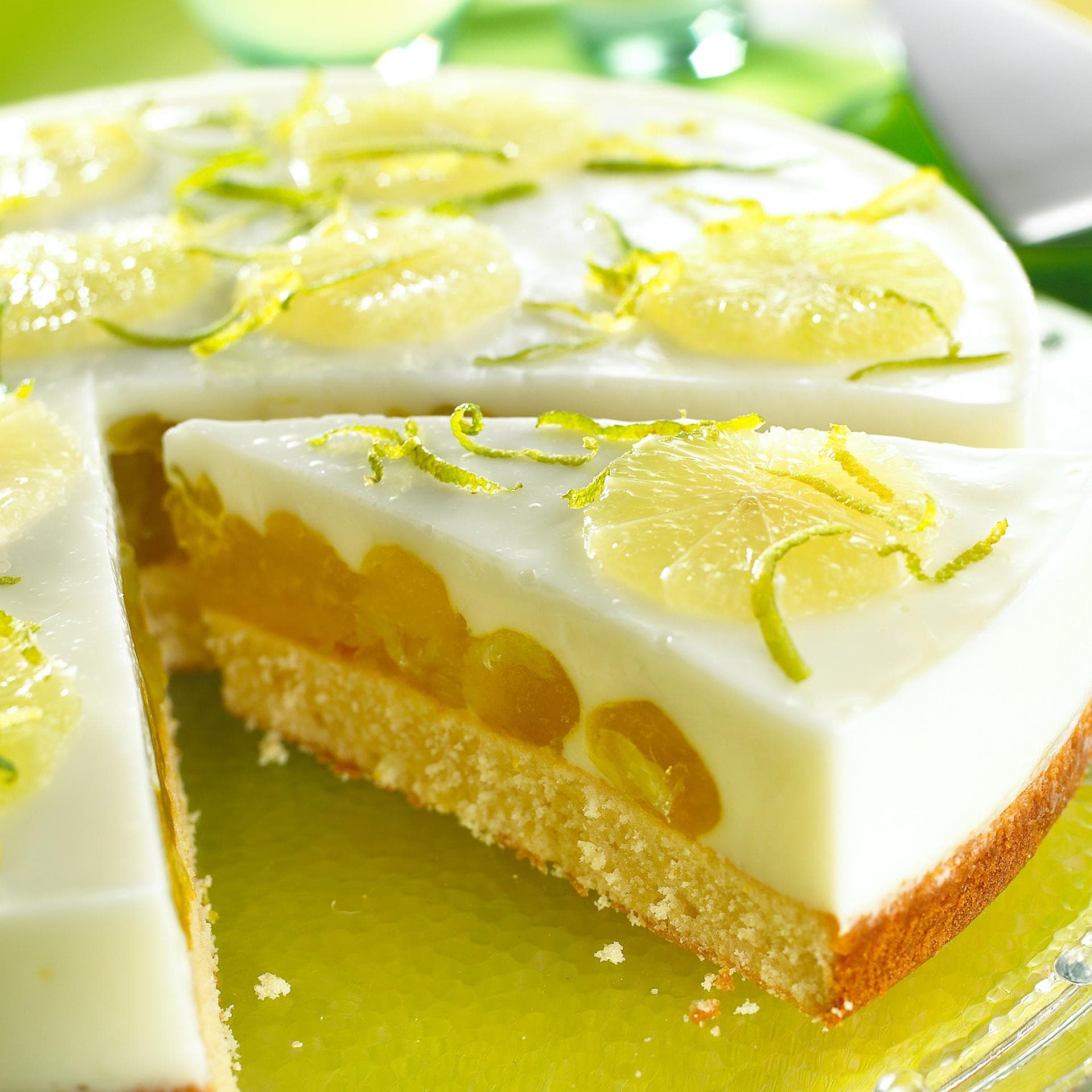 Eine Fantatorte mit Limette sieht sommerlich und frisch aus. Eine runde Fantatorte mit Limette liegt auf einer Kuchenplatte.