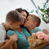 Mama freut sich über einen schönen Spruch zum Muttertag. Zwei Jungs gratulieren ihrer Mama zum Muttertag