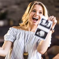 Die Schwangerschaft zu verkünden ist ein unglaublich aufregender Moment. Eine junge Frau verkündet super glücklich ihre Schwangerschaft