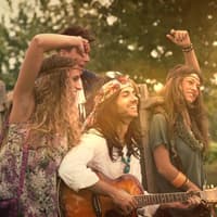 Die beliebtesten Vornamen der 70er Jahre spiegeln den Zeitgeist. Eine Gruppe junger Hippies lacht und tanzt.