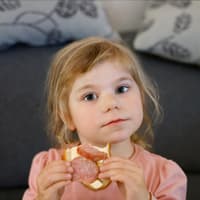 Ab wann dürfen Kinder Salami essen? Kleines Mädchen isst Brot mit Salami.