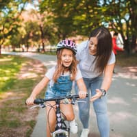 Mama bringt ihrer Tochter Fahrradfahren bei Mama bringt Tochter Fahrradfahren bei