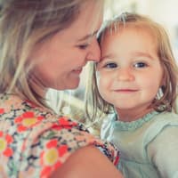 Eltern können die Resilienz ihrer Kinder maßgeblich beeinflussen. Mutter hält Tochter im Arm.