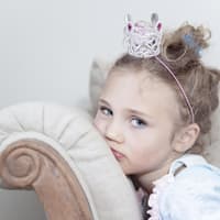 Bestimmte Erziehungsstile fördern Narzissmus bei Kindern. Kleine Prinzessin auf dem Sofa.