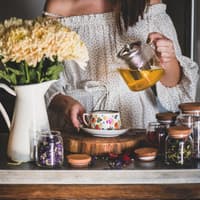 Frau schenkt sich Kräutertee ein. Frau schenkt sich Kräutertee ein.