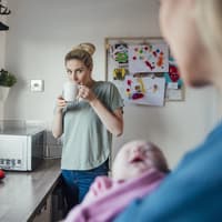 Mutter trinkt Tee, während die Oma das Baby hält. Mutter trinkt Tee, während die Oma das Baby hält.