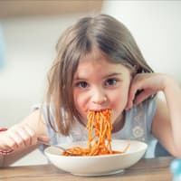 Gemeinsam essen ist schön. Ein Kind, das Spaghetti isst.