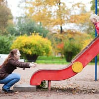 Übertrieben vorsichtige Eltern schränken ihre Kinder ein. Mutter und Tochter auf dem Spielplatz.