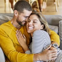 Zusammen kuscheln – auch nach Jahren Beziehung. Ein Paar, das auf dem Sofa kuschelt.