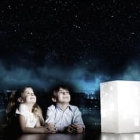 Ein Junge und ein Mädchen starren begeistert in den projizierten Sternenhimmel im Zimmer. Ein Junge und ein Mädchen starren begeistert in den projizierten Sternenhimmel im Zimmer.