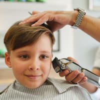 Der Edgar Cut ist zur Zeit die Trendfrisur unter Jugendlichen Ein Junge, der beim Friseur sitzt.