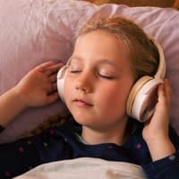 Musik oder Hörspiel zum Einschlafen, ist das okay? Ein Mädchen das Kopfhörer trägt