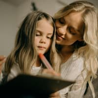 Komplimente wirken sich positiv auf das kindliche Selbstvertrauen aus. Mama umarmt ihre Tochter.