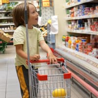 Kinder lieben die kleinen Einkaufswagen in Supermärkten Ein Junge im Supermarkt mit kleinem Einkaufswagen
