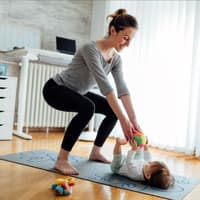 Eine Mutter trainiert ihren Beckenboden, während ihr Baby vor ihr liegt. Eine Mutter trainiert ihren Beckenboden, während ihr Baby vor ihr liegt.