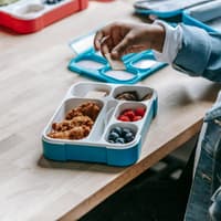 Einige Lebensmittel in der Brotdose können für Kinder gefährlich sein. Ein Junge isst einen Cracker aus seiner Brotdose.