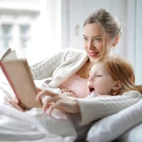 Bücher zur Einschulung, die wir empfehlen können. Eine Mutter und ihre Tochter lesen zusammen.