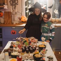 Zu Halloween lassen sich viele passende Snacks zaubern. Mutter und Kind betrachten ihr Halloween-Buffet.