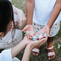 Süßigkeiten sollten nicht ohne Ende gefuttert werden. Kind und Mutter halten gemeinsam Süßigkeiten in den Händen.