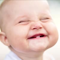 Kurze Jungennamen klingen hübsch und sind praktisch. Ein kleiner Junge grinst in die Kamera.