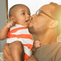 Schön klingende amerikanische Jungennamen sind auch bei uns sehr beliebt! Ein Vater küsst sein Baby.