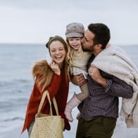 Nordische Mädchennamen werden auch hierzulande immer beliebter. Mutter, Vater und Kind gehen am Strand spazieren.