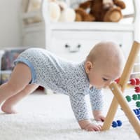 Bestimmte Lebensmittel sollen sich positiv auf die Gehirnentwicklung von Babys auswirken. Ein kleines Baby spielt mit einem Rechenschieber.