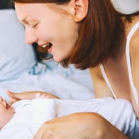 Beim Sprechenlernen hilft es dem Baby, wenn wir viel mit ihm reden. Eine Frau lächelt ihr Baby an.