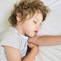 Allein im eigenen Zimmer zu schlafen, müssen Kinder erst lernen. Kleines Kind schläft im Bett.