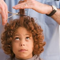 Hoffentlich geht das nicht schief: Kindern die Haare zu schneiden, ist gar nicht so leicht. Einem Kind werden die Haare geschnitten.