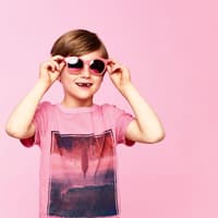 Klar dürfen Jungs Rosa tragen! Junge mit rosa T-Shirt und rosa Sonnenbrille.