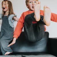 Hyperaktiv oder einfach nur gut drauf? Kinder werden heutzutage leider schnell mal mit einer Diagnose bedacht. Zwei auf dem Sofa tobende Kinder