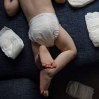 Wer kennt's? Es mieft, aber das zweijährige Kleinkind hat null Bock auf eine neue Windel ... Kleinkind mit Windelpo zwischen Windeln.