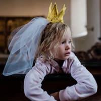 Wenn ein neues Baby kommt, müssen sich größere Geschwister erst mal an ihre neue Rolle gewöhnen. Kind, als Prinzessin verkleidet, schaut enttäuscht.