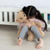 Heimweh kann bei jedem Kind mal vorkommen. Doch man kann ein Stück weit vorbeugen. Kind hat Heimweh und weint in seinen Teddy.