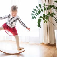 Ab wann Balance Boards geeignet sind? Auf jeden Fall schon für kleine Kinder! Optimalerweise sollten sie – anders als die geübte Turnerin hier – barfuß aufs Board.