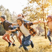 Wohl alle Kinder freuen sich über eine Schnitzeljagd! Selbst wenn es draußen kühler wird ... Kinder laufen fröhlich über eine herbstliche Wiese.