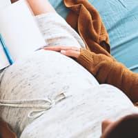 Der Mutterpass steckt voller – teils unverständlicher – Abkürzungen. Schwangere schaut sich Mutterpass und Ultraschallbild an.