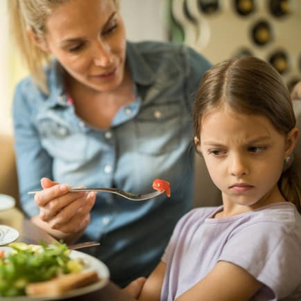 Almond Moms geben Kindern unterschwellig Diät-Tipps. Kind will den Salat von der Mutter nicht.