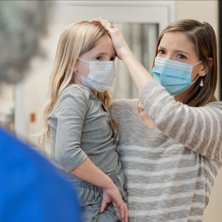 Den Kinderarzt zu wechseln, ist oft leider gar nicht so leicht. Mutter mit ihrer kranken Tochter am Empfang einer Kinderarztpraxis