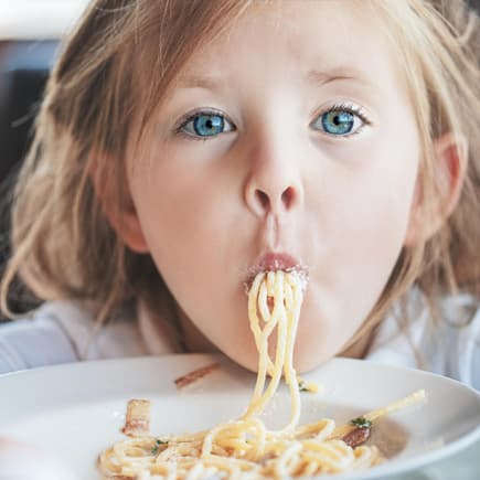 Kinder sollen Freude am Essen haben. Ein Mädchen isst Spaghetti.
