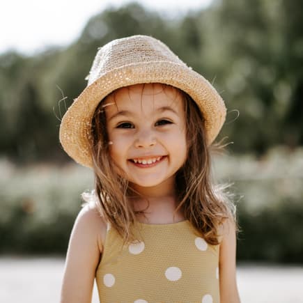 Spanische Mädchennamen klingen häufig temperamentvoll. Ein kleines Mädchen steht im Sommeroutfit am Strand.