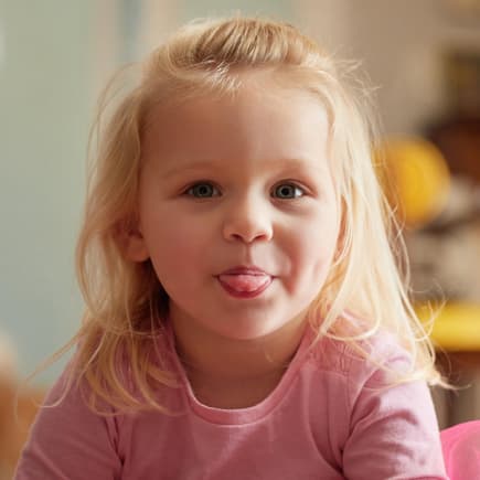Die besten Aprilscherze für Kinder Ein kleines blondes Mädchen streckt die Zunge heraus.