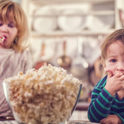 Gefahr durch Popcorn für Kleinkinder: Popcornessen ist riskant! Zwei kleine Kinder essen Popcorn